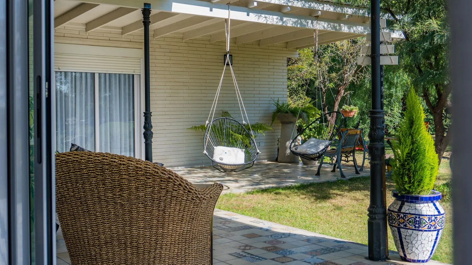 Shaded patio with hanging chairs and garden